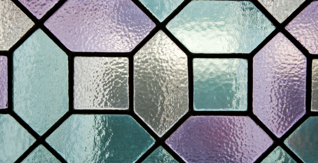 close up of leaded stained glass window with geometric pattern in soft teal lavender and frosted clear glass