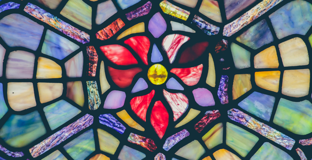 circular stained glass window with red floral centre and yellow jewel surrounded by soft purple blue and gold panes